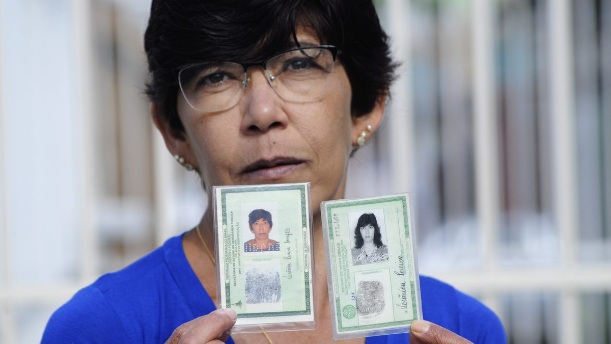 Mulher mostra duas carteiras de identidade no modelo antigo, emitidas em Minas Gerais e no Distrito Federal com números diferentes, problema que a CIN com o CPF elimina
