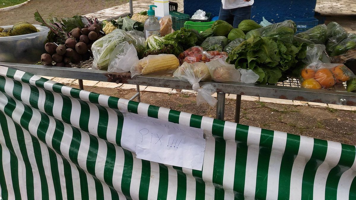 Banca de feira livre em Itajubá (MG) com cartaz escrito à mão avisando que aceita Pix
