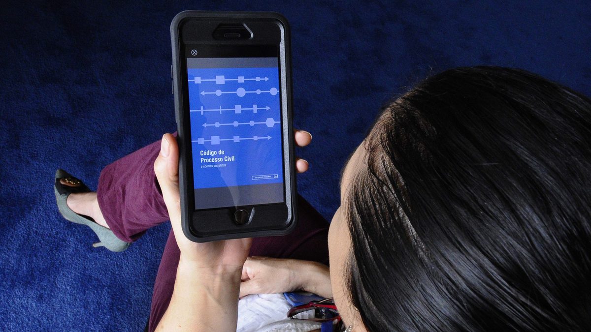 Mulher consulta o celular com as duas mãos