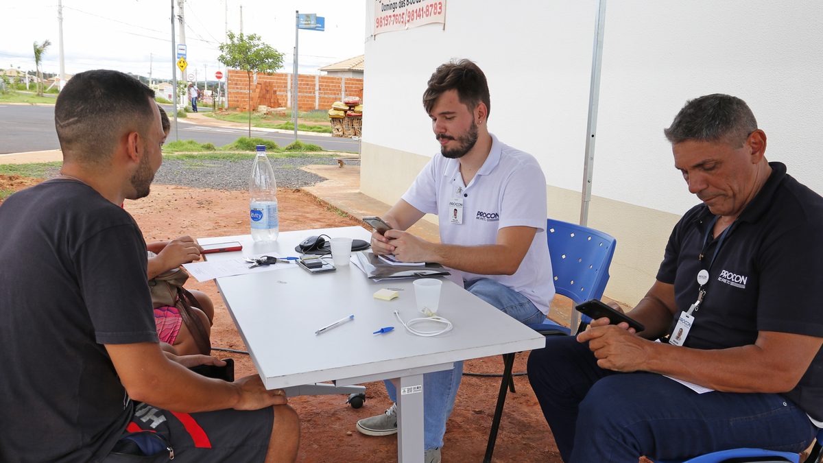 Atendentes do Procon Móvel atendem um consumidor numa mesa ao ar livre em São José do Rio Preto (SP), em dezembro de 2022