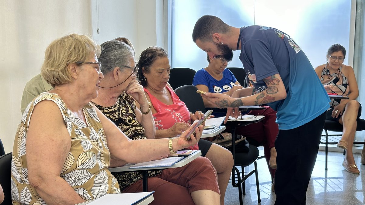 Instrutor ajuda idosas a usar o celular em curso de tecnologia em São José do Rio Preto (SP), em janeiro de 2025